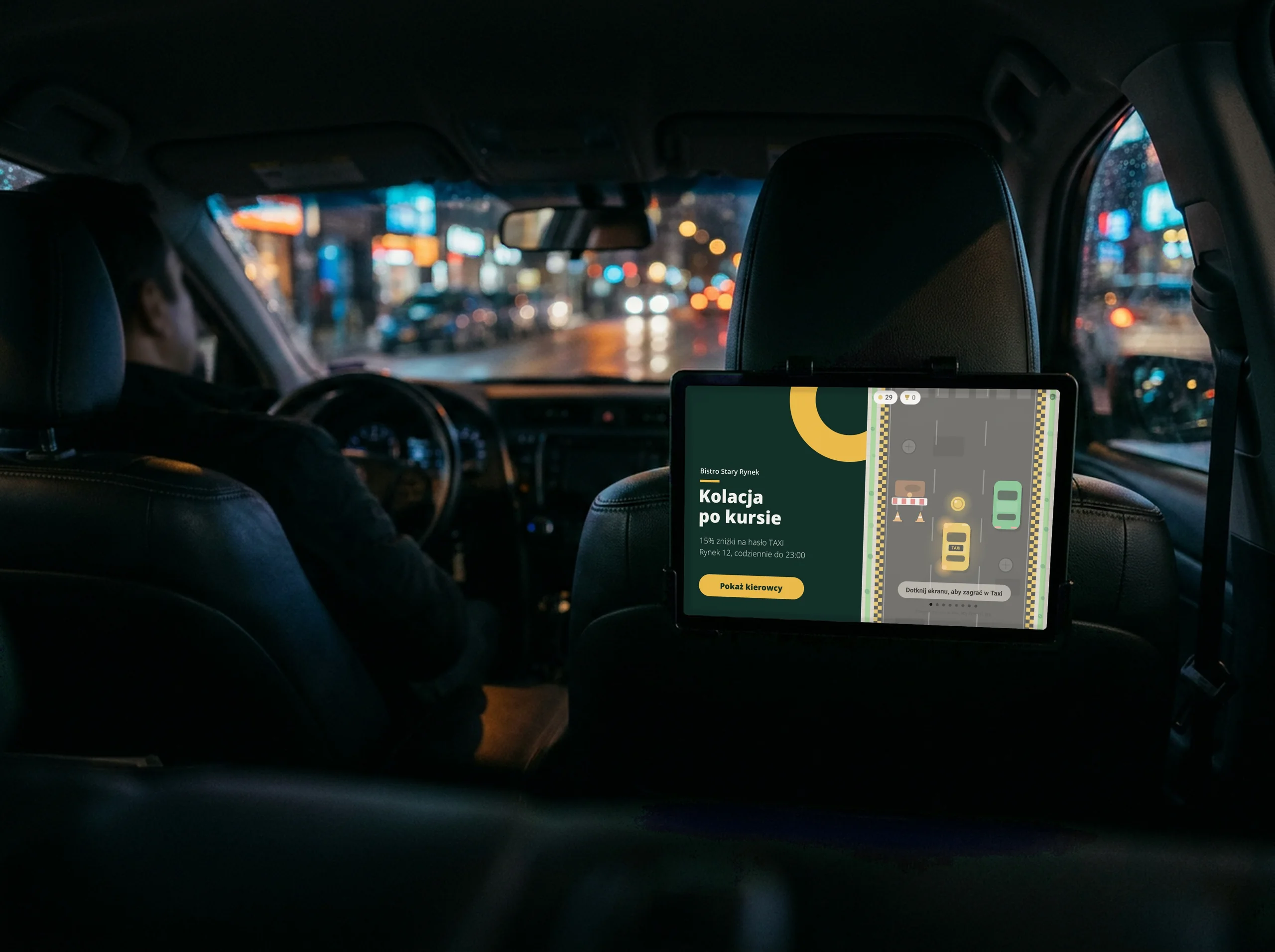 Wnętrze taksówki nocą: tablet ze ScreenTaxi za zagłówkiem wyświetla reklamę restauracji i grę Taxi