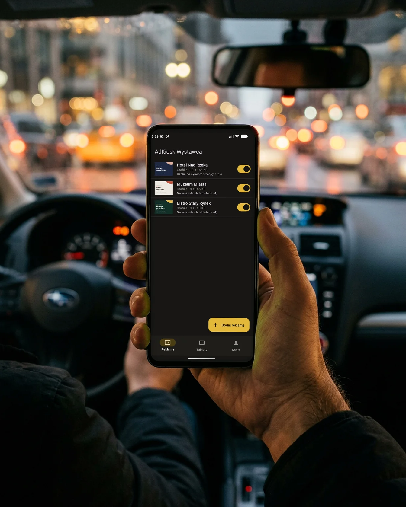 Kierowca trzyma telefon z listą reklam w aplikacji ScreenTaxi Wystawca